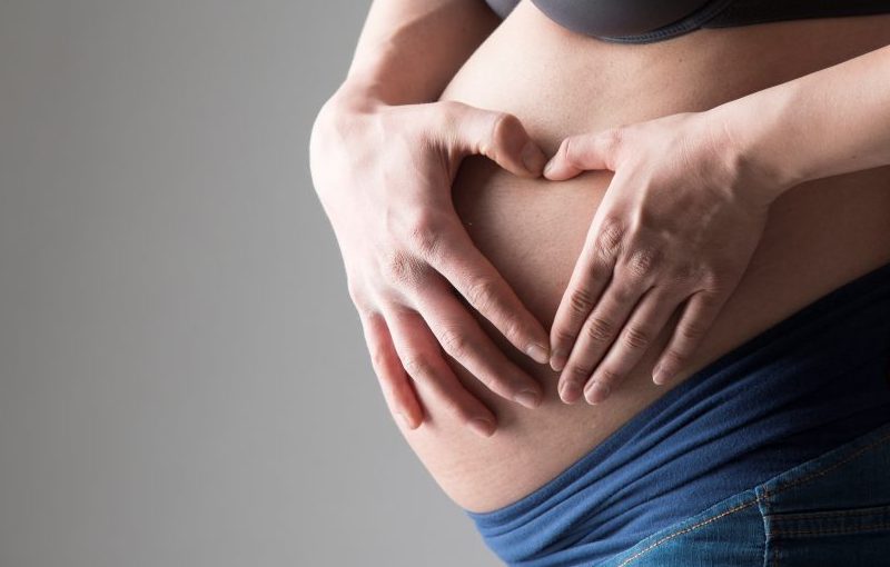 Ein Babybauch im 3. Trimester liebevoll von den werdenden Eltern berührt